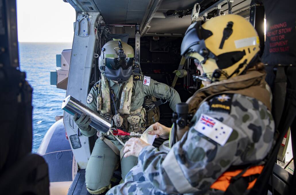 HONOURED: HMAS Albatross Chaplain Jenny Schleusener (right) and Leading Seaman Aircrewman Jacob Kambanaros conduct an airborne service in an MRH-90 helicopter from 808 Squadron for the late Commander Kenneth Barnett, OAM and his wife Rita Barnett, OAM over Jervis Bay. Photo: Cameron Martin