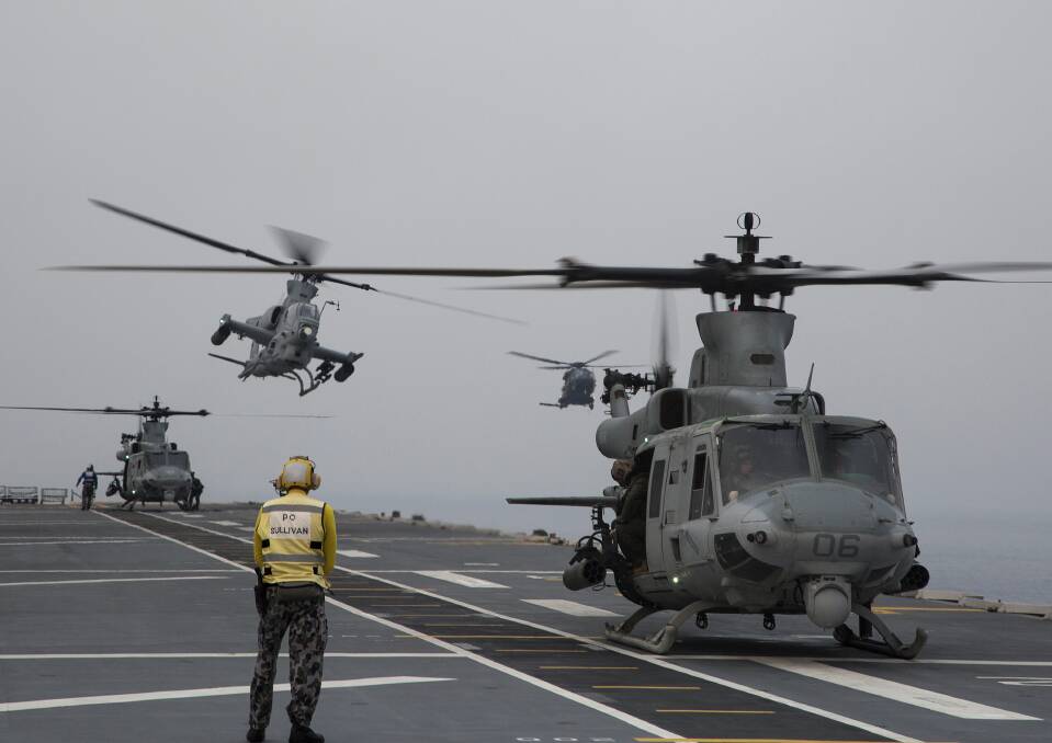 Royal Australian Navy sailor, Petty Officer Aviation Support Benjamin O'Sullivan, monitors two United States Marine Corps UH-1Y Venom helicopters as a Marine Corps AH-1Z Viper helicopter approaches HMAS Adelaide. Photo: Tara Byrne.
