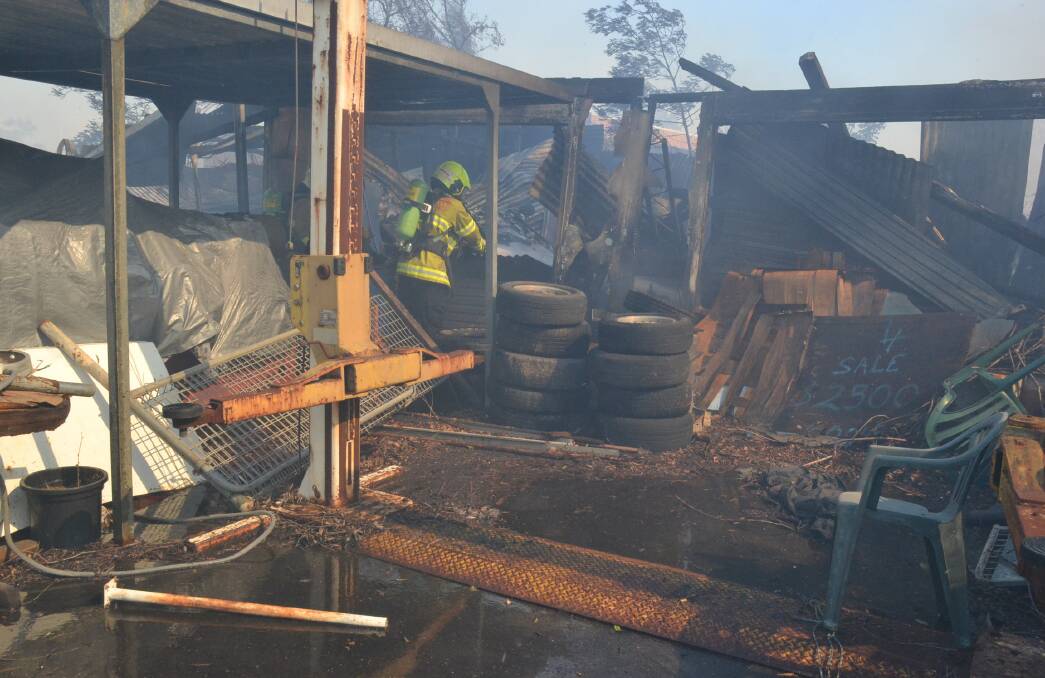 Fire and Rescue NSW crews blacken out the shed that was destroyed at Bomaderry in the West Cambewarra Road fire. Photo: Damian McGill