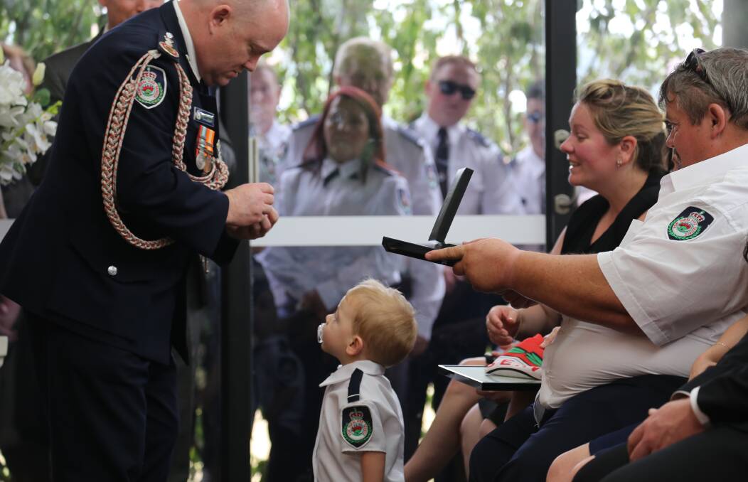 RESPECT: Another of James Morris' photos from Geoff Keaton's funeral, with young Harvey Keaton looking up at the then NSW RFS Commissioner Shane Fitzsimmons just prior to the official presentation.