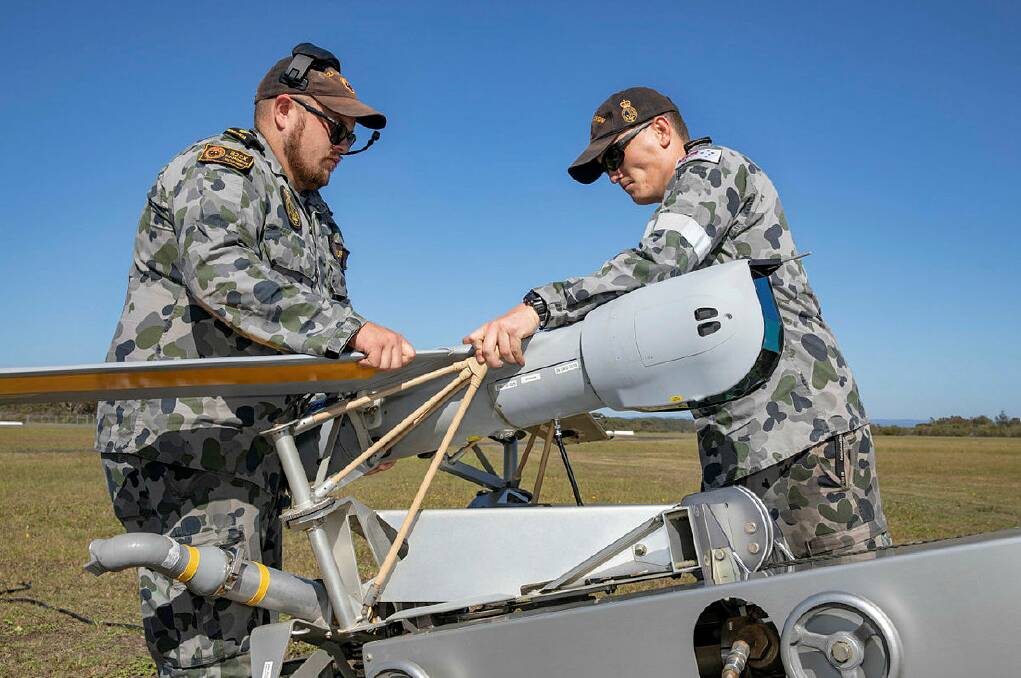 FLIGHT TIME: 822X Squadron members Able Seaman Combat Systems Operator Garreth Laurie (left) and Able Seaman Aviation Support Luke Williams load a ScanEagle Unmanned Aircraft onto the pneumatic catapult prior to launching at Jervis Bay airfield. Photo Cameron Martin
