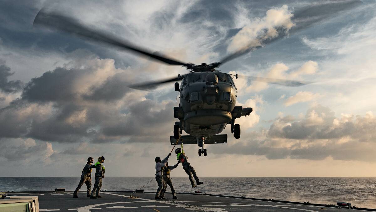  MANOEUVRE: HMAS Toowoomba's MH-60R helicopter conducts a personnel transfer at sea while en-route to South East Asia. Photo: Steven Thompson