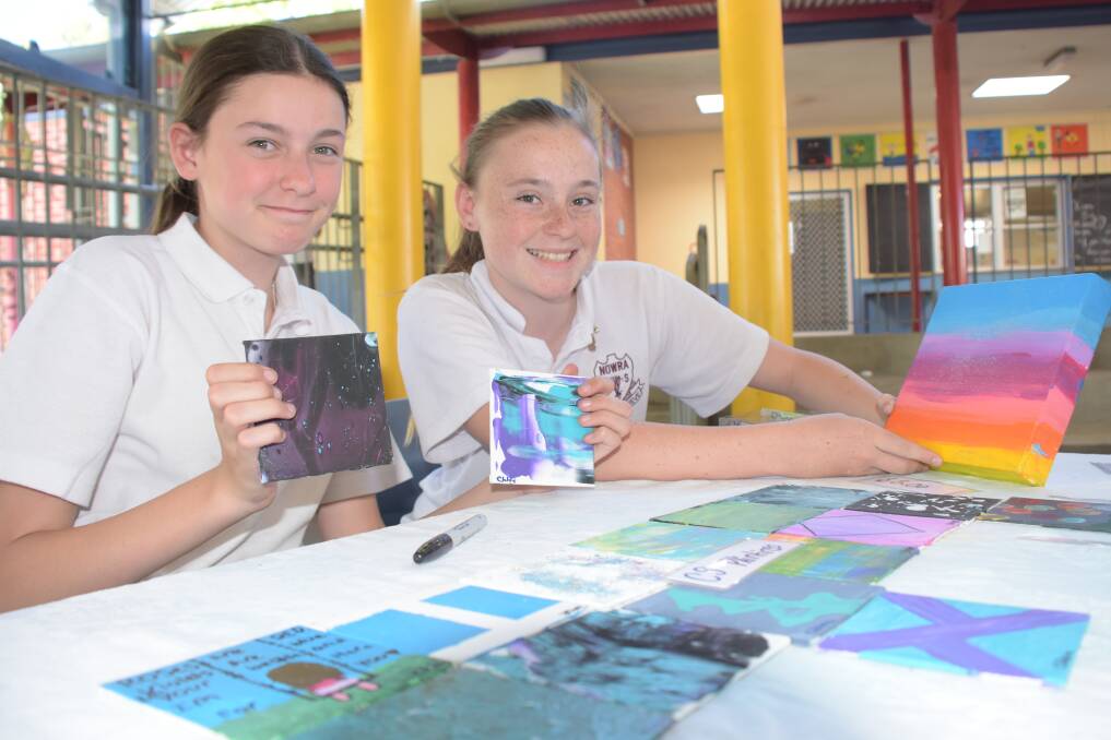 Chloe Nelson and Skye Wood show off their paintings.