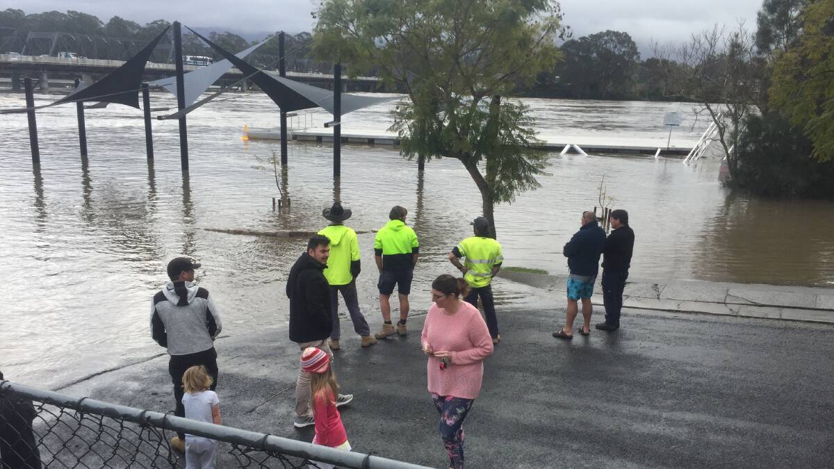 HOW HIGH: Locals gather at the site of the former Nowra Sailing Club at the Shoalhaven River during August's floods.
