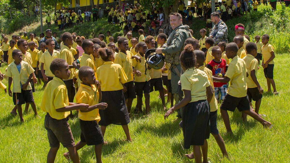 Leading Seaman Aircrewman Brendan Menz is surrounded by students during a visit to Erakor Bilingual School in Erakor Village, Vanuatu. Photo: Justin Brown