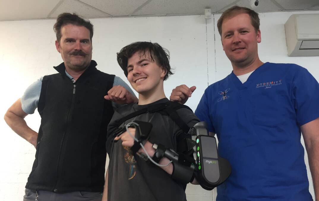 BIONIC MAN: Nineteen-year-old Khy Antoniazzo with his new MyoPro powered arm with his caseworker/physiotherapist Damien Barratt (left) and Jens Baufeldt, of X-Tremity Prosthetics and Orthotics in Nowra.