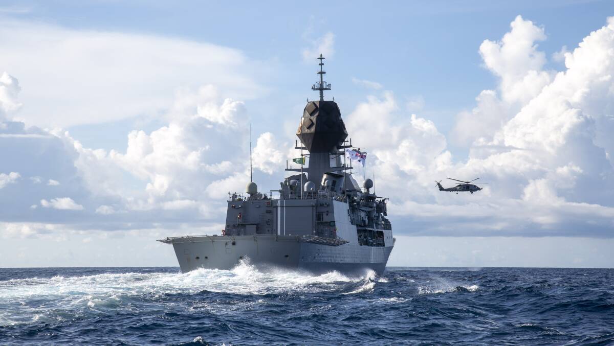 SUPPORT: A MH-60R helicopter flies over HMAS Anzac. Photo: Rikki-Lea Phillips
