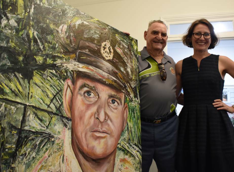 Victoria Cross recipient Keith Payne with doctor Kate Manderson in her Nowra practise with the portrait of Mr Payne she purchased at this year’s Digger Day Ball auction.