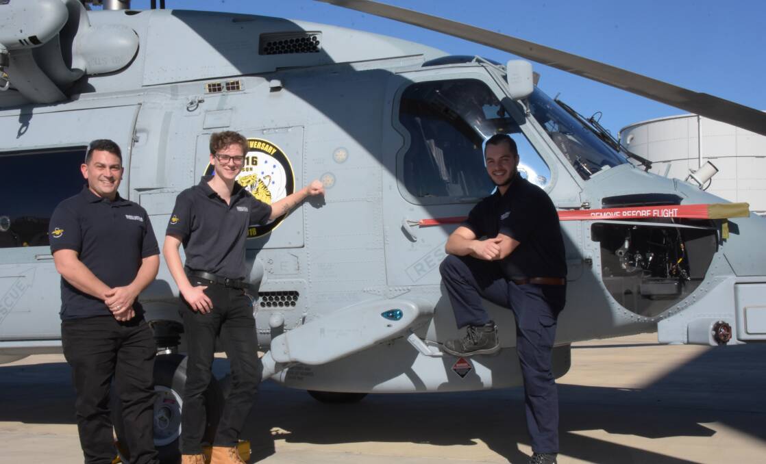 New Sikorsky Australia apprentices Joel Grimston, Nicholas Poelczer and Luca Taglieri with a Royal Australian Navy MH-60R (Romeo) maritime helicopter they will son be working on.