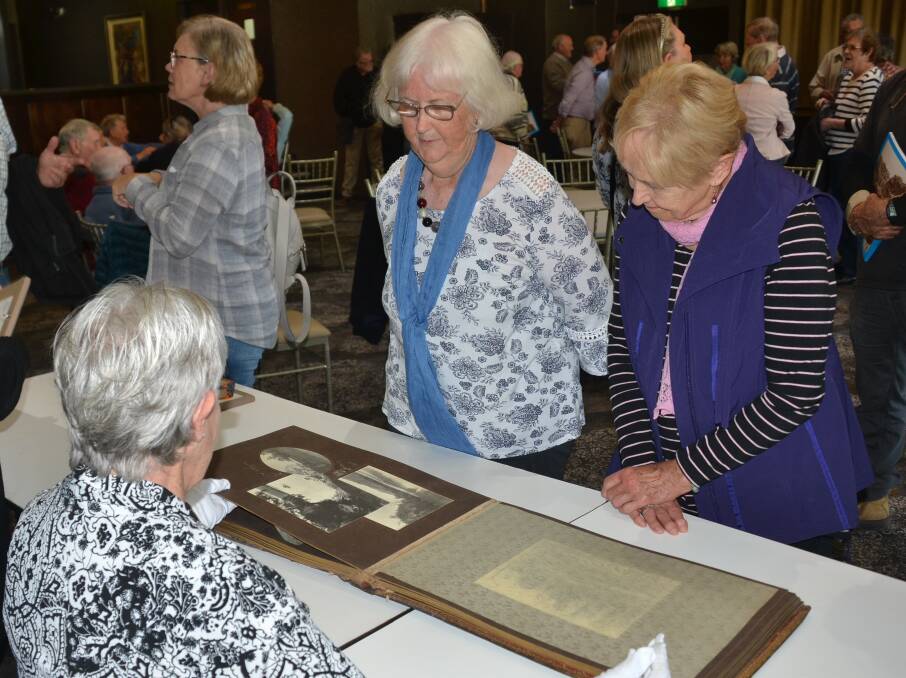 INCREDIBLE: Heather Williams and Kathy Jones look over an album of Samuel Cocks photographs for the Hugh Mackenzie album which also includes a superb illuminated address, with Shoalhaven Historical Society member Gerri Walker.