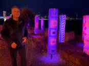 Nowra artist and TAFE teacher Warwick Keen checks out the installation of his Indigenous tree-carving inspired pillars lit up as part of the Vivid Festival. Pictures: Adam Wright. 