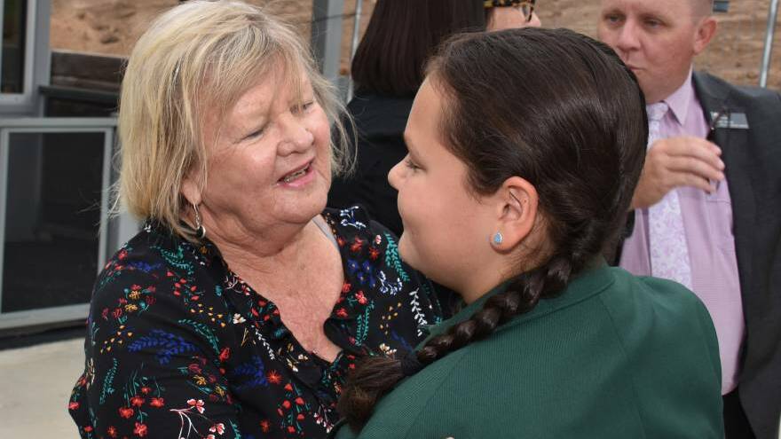 Glen Innes Severn mayor Carol Sparks, who lost her own home in the Wytaliba fire, welcomes a student to her first day back at the town's hastily rebuilt school.