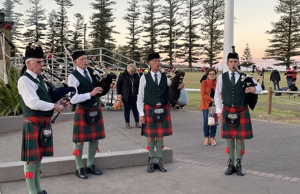 POST COVID LIFE: The Kiama Pipe Band plays at the conclusion of a choral concert in Kiama, with a footy game underway on the oval behind. Photo by Kathy Sharpe