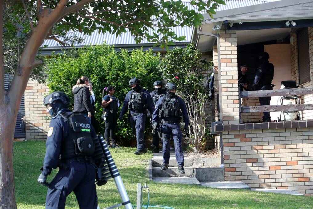 Police converge on the lawn of Elias Elchaar's Figtree home during a raid on Monday. 