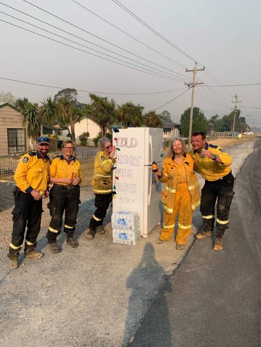 Firies enjoying a cold drink thanks to the fridge set out by the Hooper family of Bungendore. Picture: Courtesy of the Carwoola Rural Fire Brigade