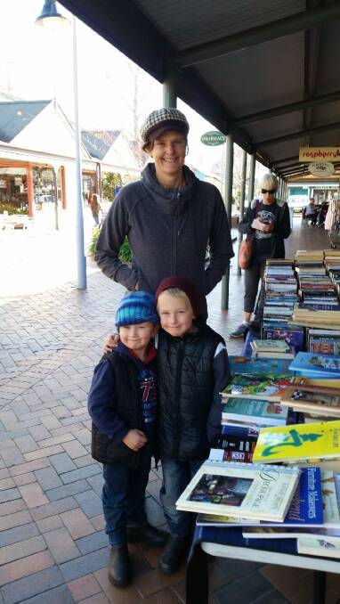STOCK THE BOOKSHELF: Banjo, Archie and their mum pick up a bargain at the stall last year during their travels around Australia. Photo contributed. 