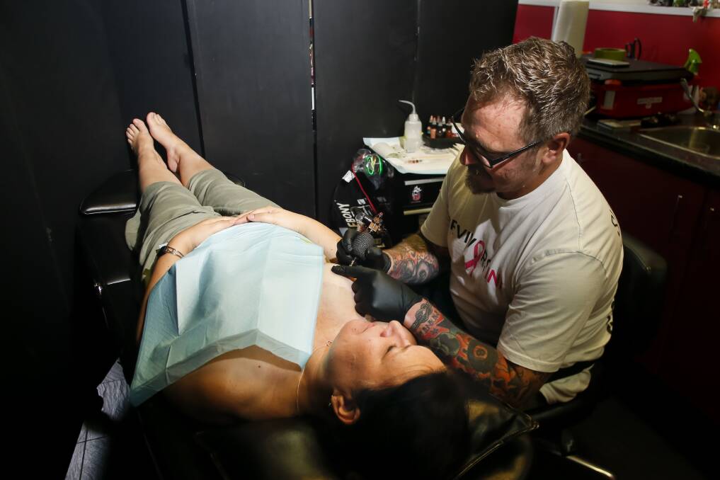 IMPORTANT SERVICE: Breast cancer survivor Judith Carrall, and tattoo artist Peter Bone (aka Bones) from Survivors Ink at Crown Ink Tattoo Studios, Wollongong on Sunday. Picture: Anna Warr
