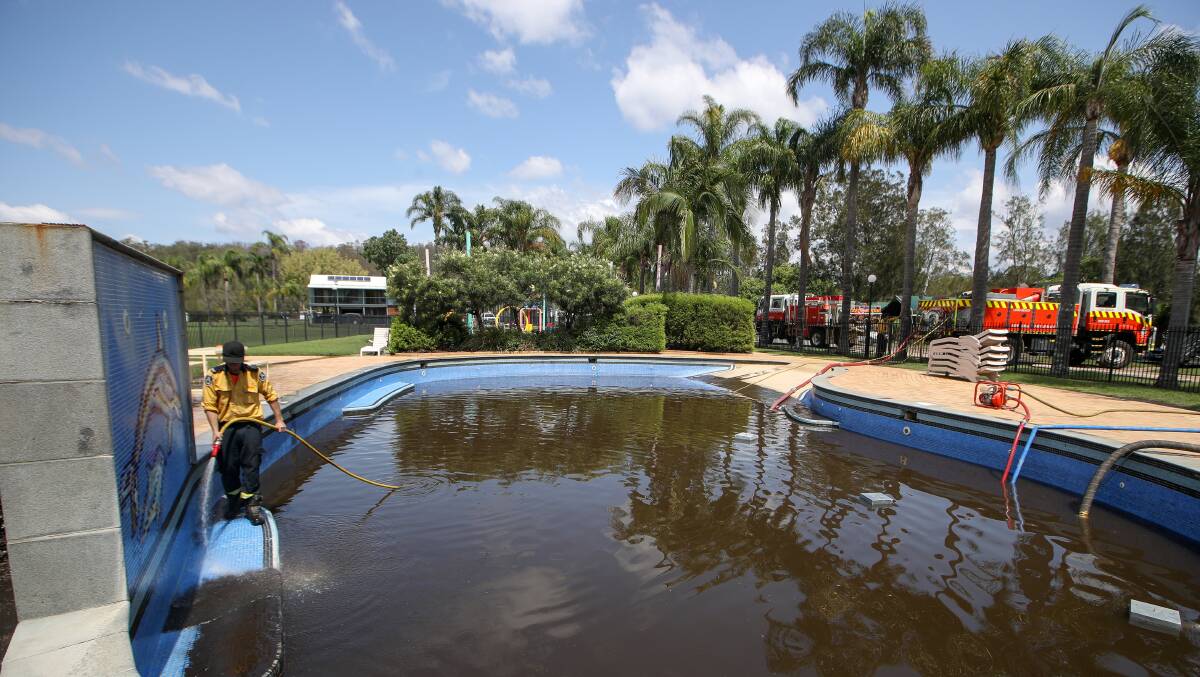 An RFS crew member pumps the brown water out of the pool. Photo: Adam McLean