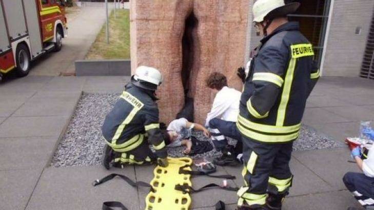 Rescuers works to free the young man trapped in a sculpture of a vulva at Tubingen, Germany. Photo: Imgur