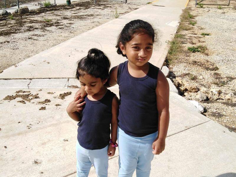 Guards will accompany the detained Tamil family's Kopika (right, with sister Tharunicaa) to school.