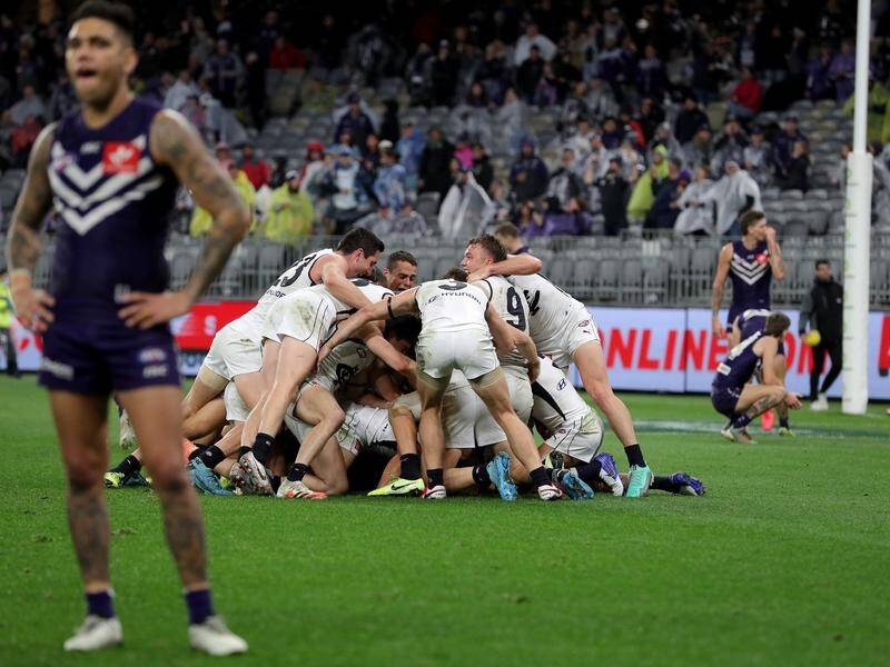 Carlton players celebrate their dramatic win at Optus Stadium as Fremantle players lament defeat.