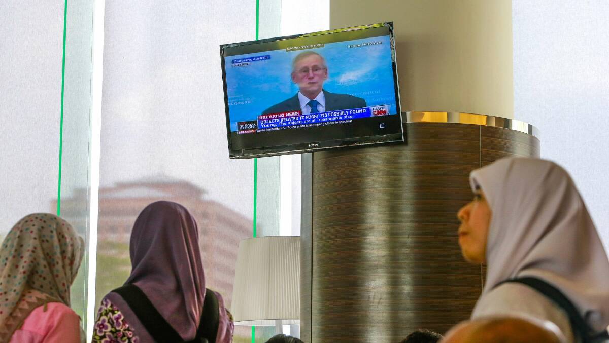 Journalists look at a television screen at an announcement from John Young, general manager of the emergency response division of the Australian Maritime Safety Authority (AMSA), about satellite imagery of debris possibly from Malaysia Airlines flight MH370 inside the hotel where are relatives of the passengers of the missing Boeing 777-200ER are staying in Putrajaya March 20, 2014. Photo: Reuters.