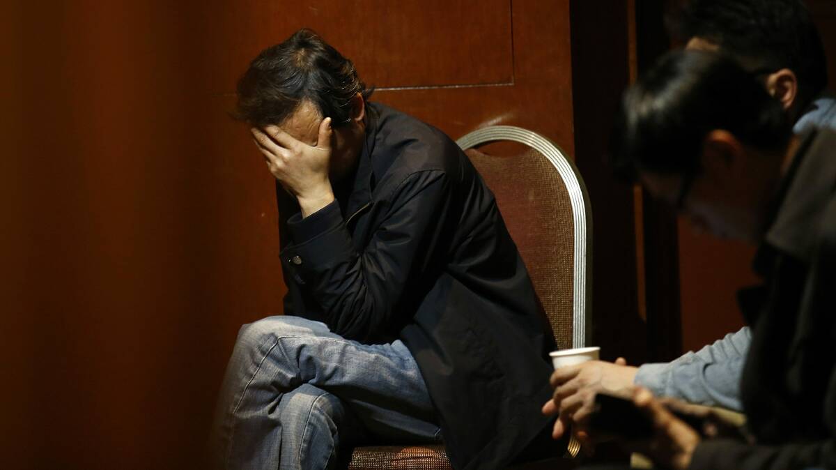 A man covers his face as he waits for information about passengers onboard the missing Malaysian Airlines flight MH370 in a room at the Lido Hotel in Beijing, March 20, 2014. Photo: Reuters.
