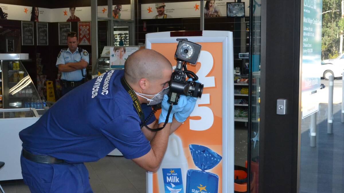 A Forensic Services officer photographs the crime scene at the Star Mart Caltex Service Station at South Nowra after a robbery on Thursday evening.