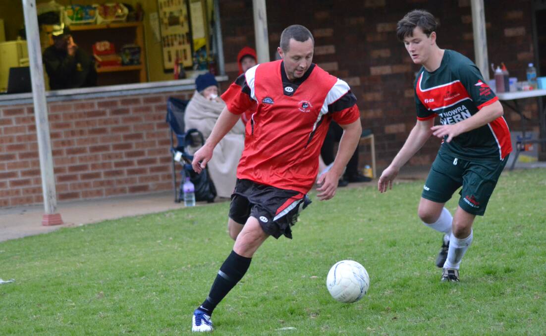 CHALLENGE: Shoalhaven United’s Chris Button tries to get the ball around Illaroo’s Daniel Hockey in their team’s 2-all draw on Saturday at Sharman Park. Photo: PATRICK FAHY    