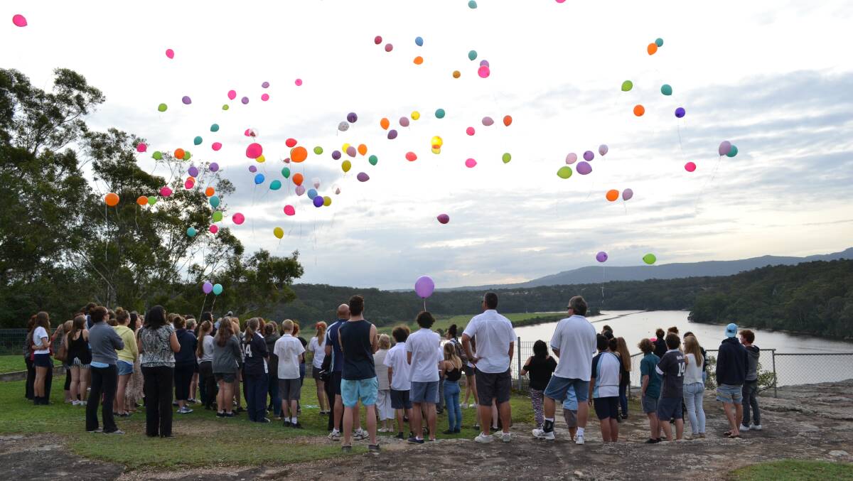 MEMORIES: Friends comfort one another and colourful balloons are let loose at Nowra Showground during a memorial for Nowra High schoolgirl Sarah Blank.