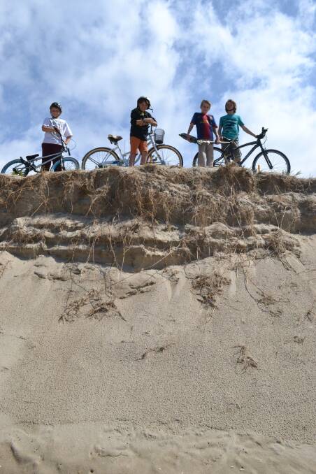 Bike riders look down over the towering sand dunes at Shoalhaven Heads.