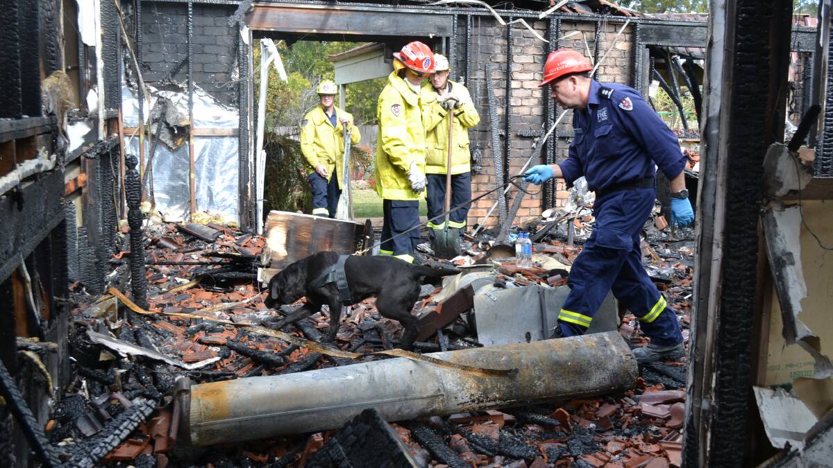 SEEKING THE SOURCE: Fire and Rescue NSW firefighters and investigator Phil Ettienne scoured the burned home, with an accelerant detection dog on Friday.
