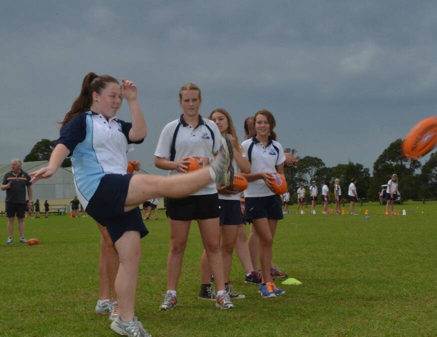 Nowra High School year 8 student Elise Thomas boots the ball during Australian Football training at the Girls Get Active Schools Day in Bomaderry.