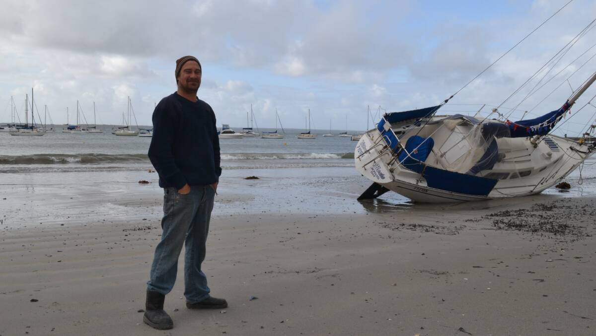 ROUGH GOING: Ulladulla man David Boonaerts inspects the damage to washed up yachts at Callala Bay.