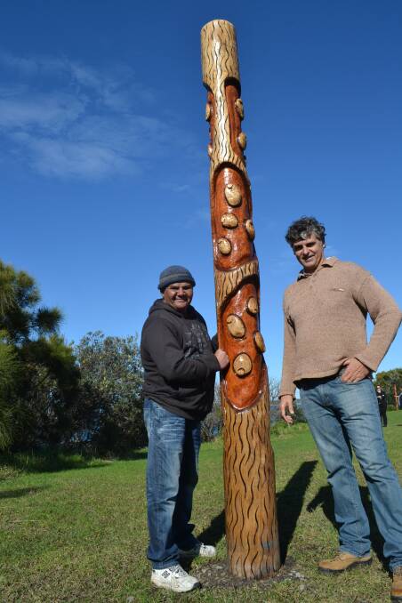 SCARRED: Noel and Alfred Wellington stand among the eight carved logs which represent Indigenous tree scarring methods to depict the local people’s strong connection to the land and sea with images of water ripples, abalone, oysters and pipis, lobsters, fish and octopus.