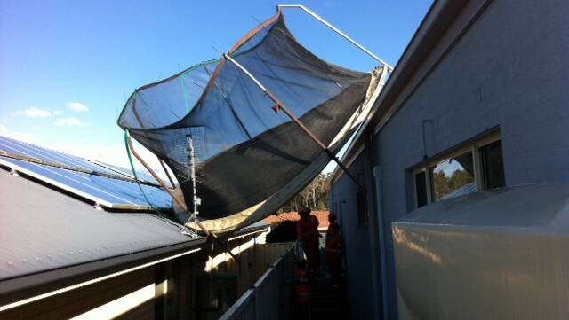MISSILE: SES volunteers remove a trampoline blown on to the roof of Ekidna Kinda at West Nowra.