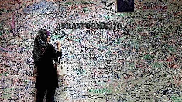 A woman writes on the message board in support of the passengers and family members of the missing Malaysia Airlines Flight MH370, at a shopping mall in Damansara near Kuala Lumpur. Photo: REUTERS 