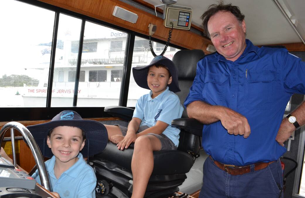 LET’S GO: Huskisson Public students Kane Scruse and Otto Isaac at the helm of the Marine Rescue NSW Jervis Bay vessel The Colin Woods with master Peter Kielar.