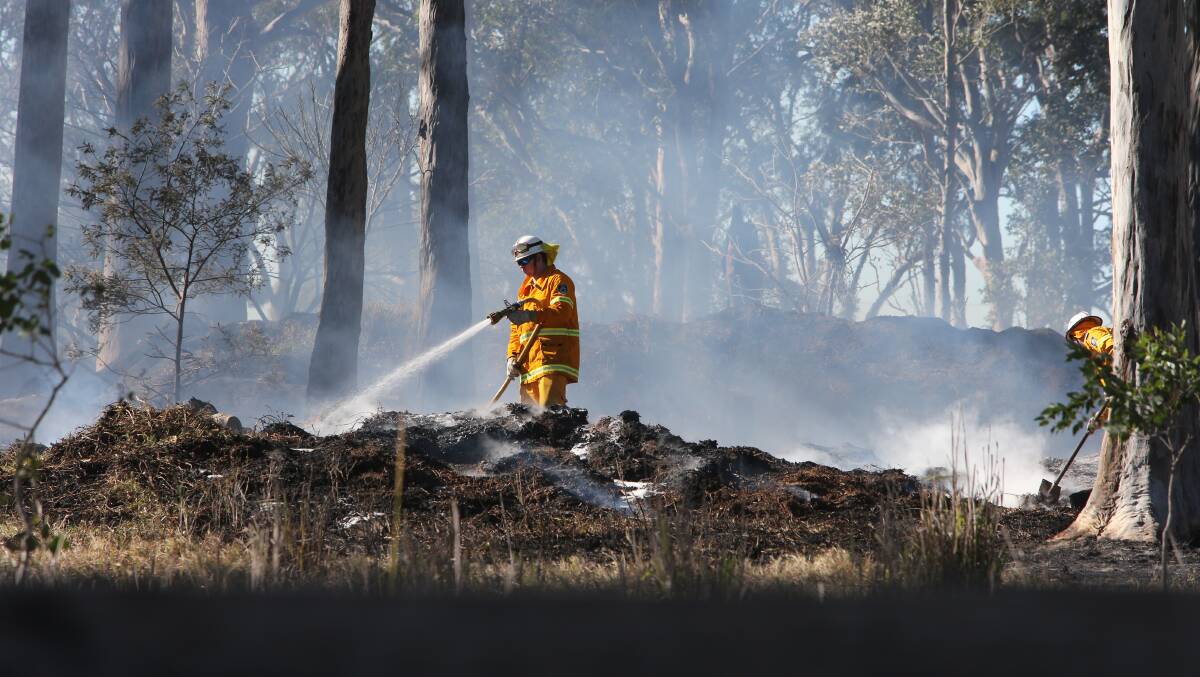 MOPPING UP: Fire crews continue to blacken out the fire at the Worrigee property on Saturday morning, with an excavator brought in to break up some of the smouldering piles of wood.
