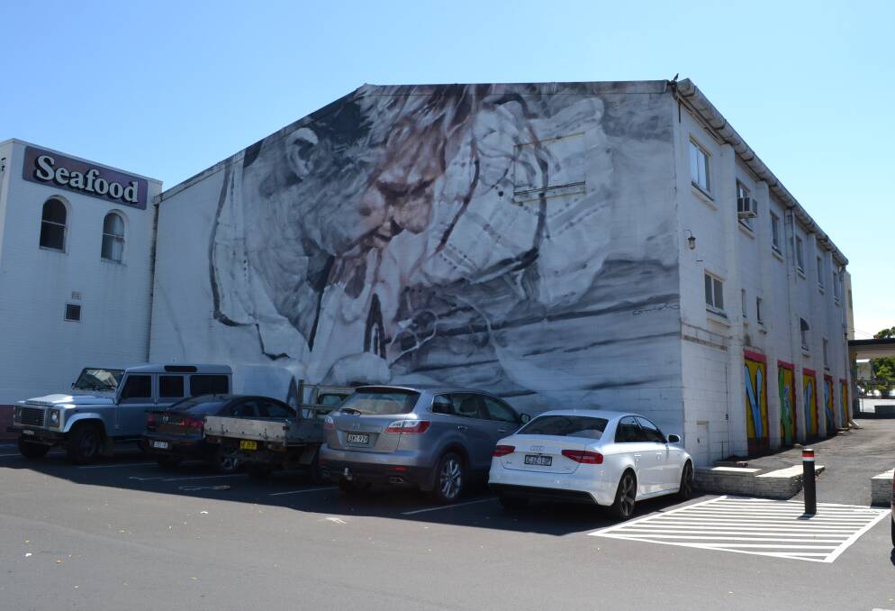 SECRET’S OUT: International artist Guido Van Helten has brought the entrance to Nowra’s live gallery walk to life with his interpretation of a picture taken by the late Jeff Carter of a fisherman mending a net in Greenwell Point in 1955.