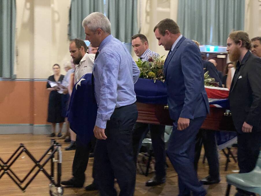 Paulbearers carry Wes' coffin into the Nowra School of Arts building. 