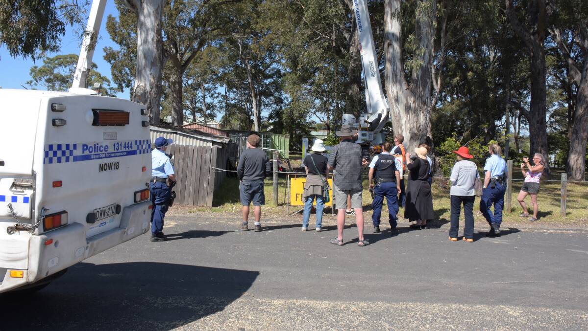 Police officers and protesters standing outside of the Huskisson Anglican Church site after the protester had been taken away. 