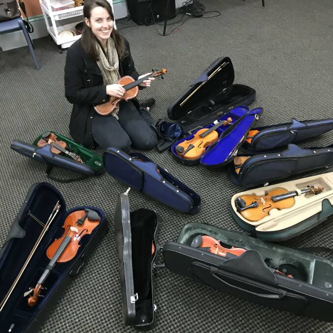 Eryn Deys, SYOs Junior Strings conductor looking over the 10 violins that have been donated.