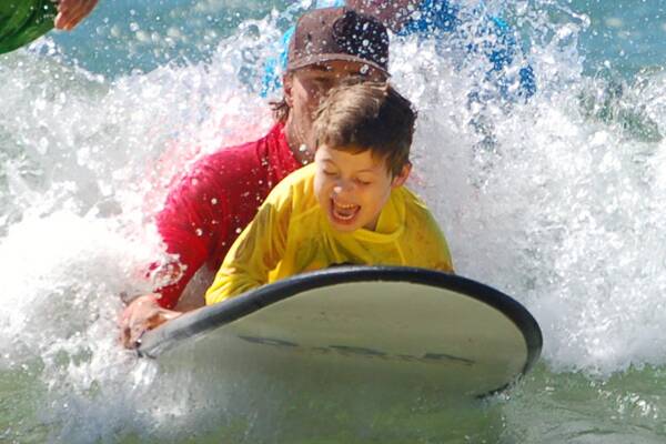 GREAT TIME: Paul Scholten hits the surf with a new friend during an annual Gerroa Hands On Day.