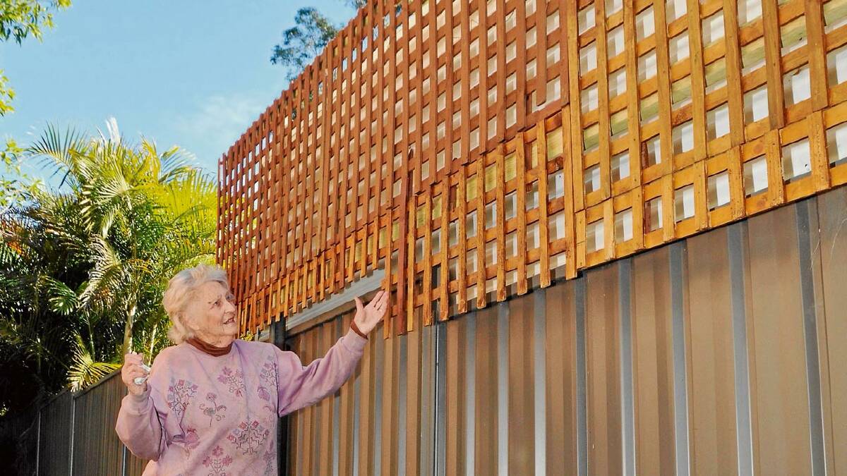 MIGHTY HIGH: Audrey Gardyne takes in the proportions of the privacy fence her neighbour erected on their boundary fence while she was on holiday.